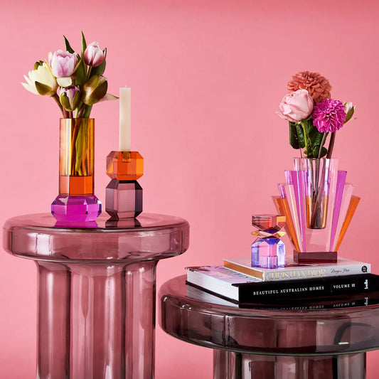 Styled shot of glass accent tables styled with colourful crystal vases and candle holders